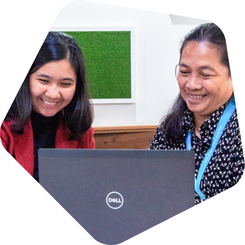 Two individuals working on a Dell laptop in an office setting.