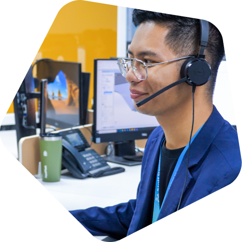 A person with headphones at a workstation with multiple monitors and office equipment.