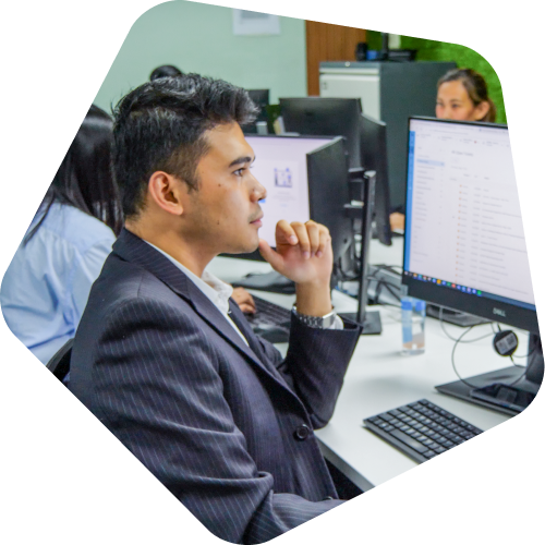 A professional in a suit working at a computer in an office environment.