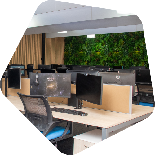 Modern office with computers on desks and a green living wall in the background.