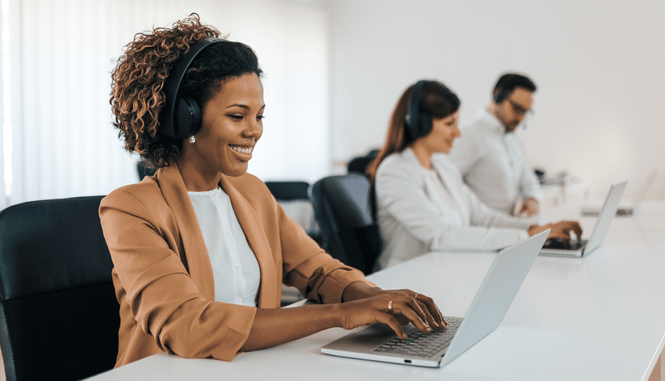 outsource-customer-service-employee-smiling-at-her-desk