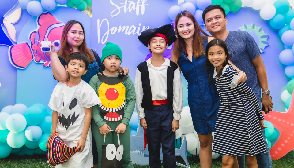 A group of people posing for a photo at a colorful event with balloon decorations in the background.