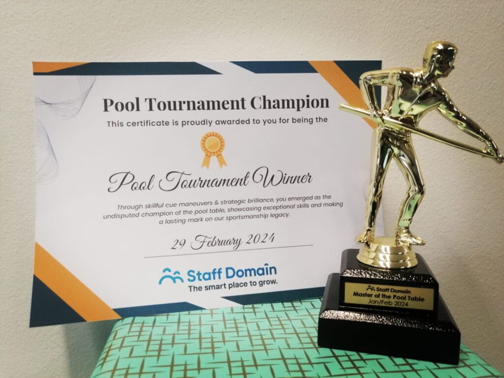 A trophy and a certificate on a pool table, recognizing the champion of a pool tournament.