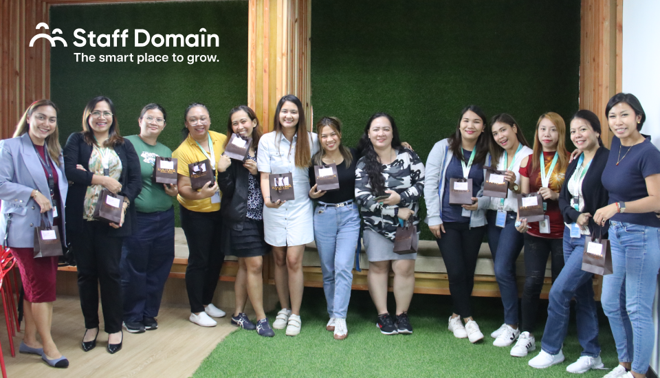 Group of people holding awards in an office with a "Staff Domain" logo on the wall.
