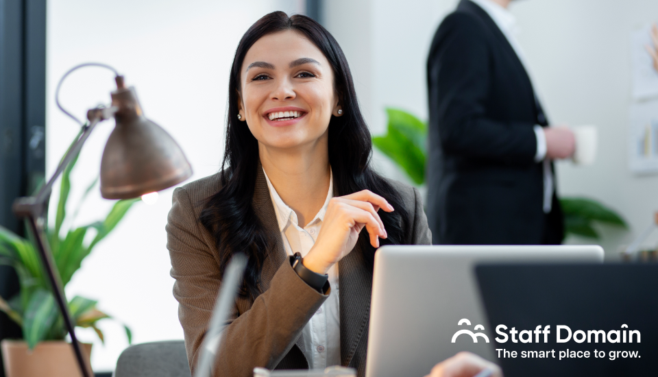 A professional woman working on a laptop in a modern office setting.