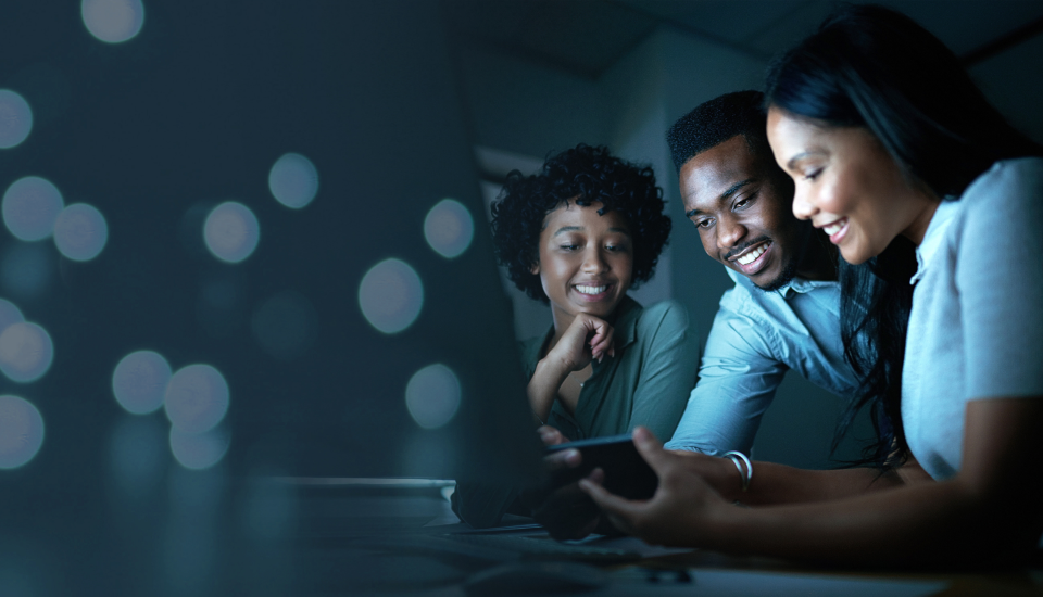 Two people looking at a smartphone in a dimly lit room with bokeh lights in the background.